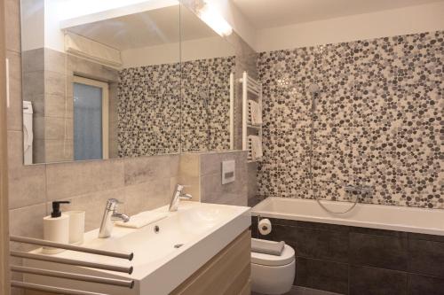 een badkamer met een wastafel, een toilet en een bad bij JobelHome Castle District Apartments in Boedapest
