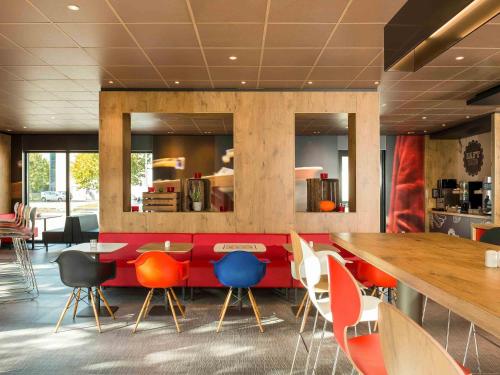 a restaurant with colorful chairs and a long table at Ibis München Airport Süd in Hallbergmoos