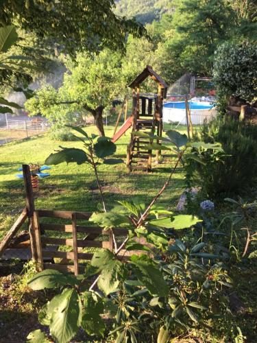 a playground in a garden with a wooden fence at Agriturismo LA TAVERNA DEL NONNO in Borzonasca