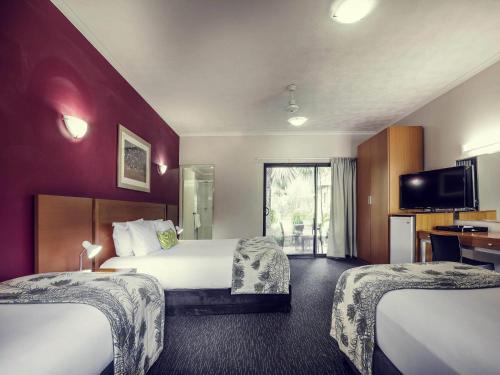 a hotel room with two beds and a flat screen tv at Mercure Darwin Airport Resort in Darwin