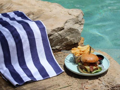 a sandwich and french fries on a plate next to a towel at Mercure Darwin Airport Resort in Darwin
