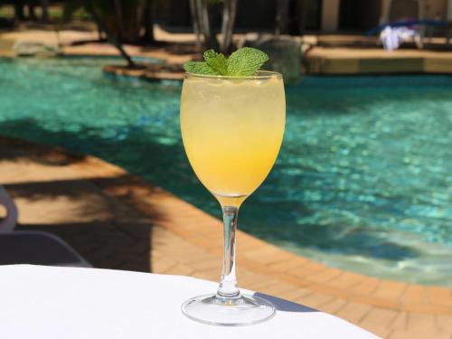 a drink sitting on a table next to a pool at Mercure Darwin Airport Resort in Darwin