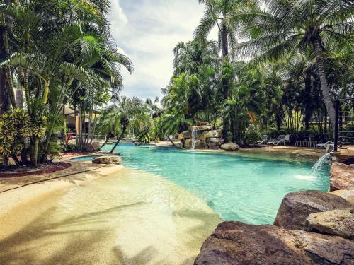 a pool of water with palm trees in a resort at Mercure Darwin Airport Resort in Darwin