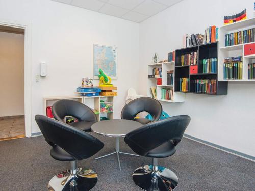a room with four chairs and a table and bookshelves at Aabenraa Camping in Aabenraa