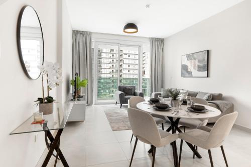 a white living room with a table and chairs at Stylish 1BR in Wasl 1 with Balcony & Pool in Dubai