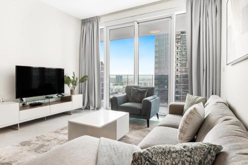 a living room with a couch and a tv at Stylish 1BR in Wasl 1 with Balcony & Pool in Dubai