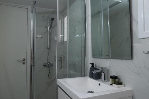 a bathroom with a sink and a shower with a mirror at Limassol Sunbliss by Staycom in Limassol