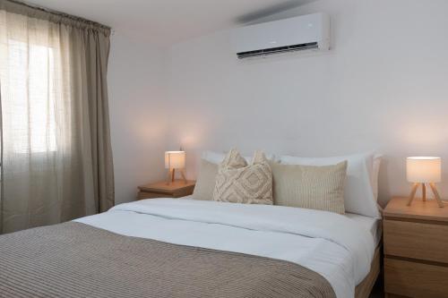 a bedroom with a white bed with two lamps at Limassol Sunbliss by Staycom in Limassol