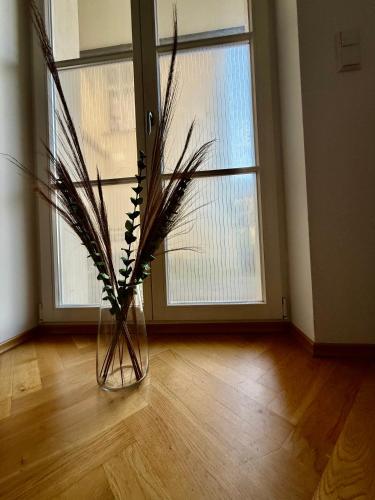 a vase with branches in it on a wooden floor at Modernes Apartment im Süden Leipzigs in Leipzig