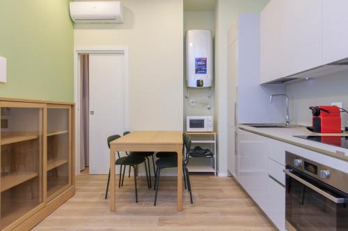 a small kitchen with a wooden table and chairs at I-Host Apartment - Ripamonti 205 in Milan