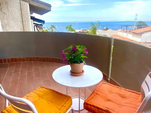 a table with two chairs and a plant on a balcony at Marilù e il Mare - Your home by the sea in Aci Castello