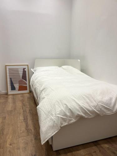 Una cama blanca en un dormitorio blanco con una foto en Ultra-Central Cozy Studio, Steps from Everything, en Cluj-Napoca