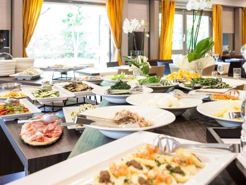 a long table filled with plates of food at Novotel Brescia Due in Brescia