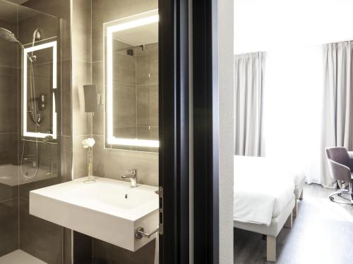 a bathroom with a sink and a shower and a bed at Novotel Brescia Due in Brescia