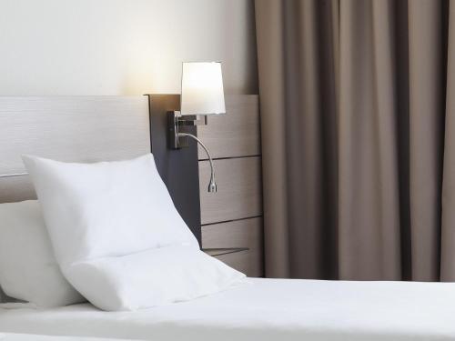 a bed with a white pillow and a lamp at Novotel Brescia Due in Brescia