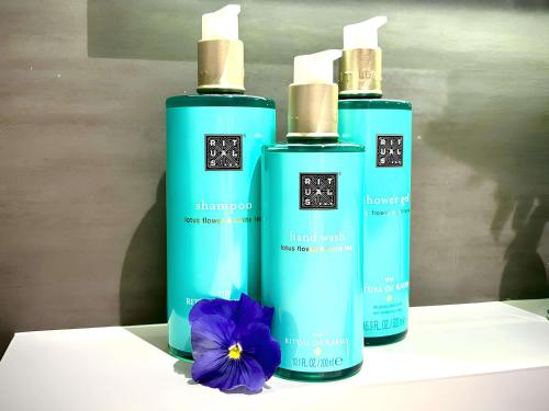three bottles of shampoo and a flower on a table at Novotel Brescia Due in Brescia