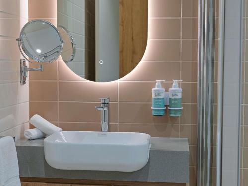 a bathroom with a white sink and a mirror at Novotel Darwin Airport in Darwin