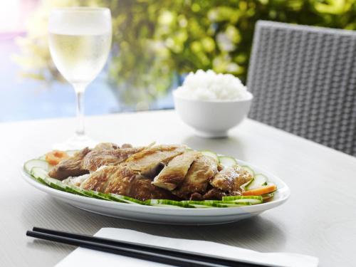a plate of meat and vegetables with a glass of wine at Novotel Darwin Airport in Darwin