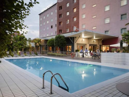 a large swimming pool in front of a hotel at Novotel Brescia Due in Brescia