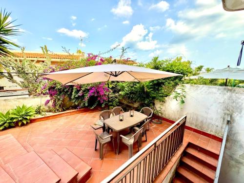 a patio with a table and chairs and an umbrella at Marilù e il Mare - Your home by the sea in Aci Castello