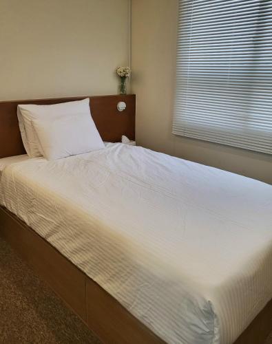 a large bed with white sheets and a window at jeonju hotel book and type in Jeonju