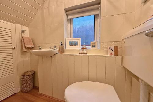 Un baño con inodoro, lavabo y ventana. en Morrison Park - West Strand Portrush, en Portrush