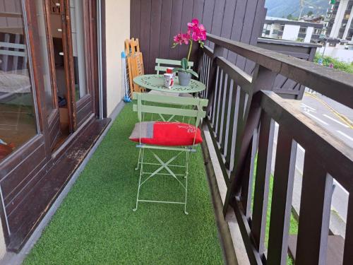 a table and chairs on a balcony with green grass at Le Sapi 1E Balcon panoramique Aiguilles Rouges avec parking gratuit in Chamonix-Mont-Blanc