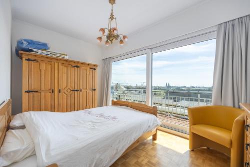 1 dormitorio con cama, silla y ventana grande en Royal Coastline Comfort - 221, en Middelkerke