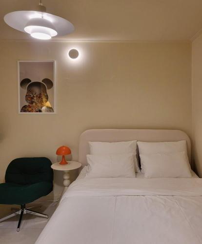 a bedroom with a white bed and a green chair at jeonju hotel book and type in Jeonju