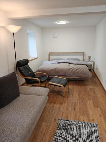 a bedroom with a bed and a couch and a chair at Chalet am Bärenpfad in Neuschönau