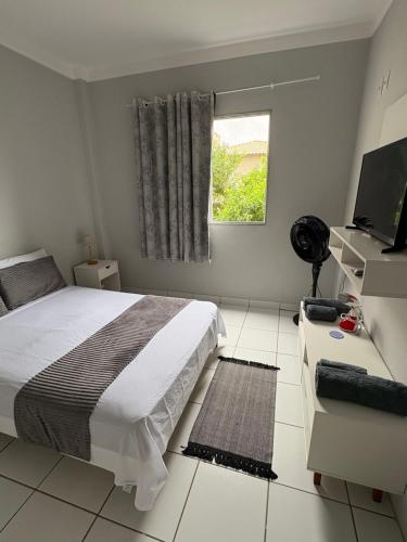 a bedroom with a bed and a desk and a window at Bertholi Beira-Mar in Serra
