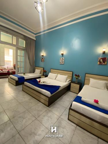 a bedroom with three beds and a blue wall at Hostgram Hotel in cairo in Cairo