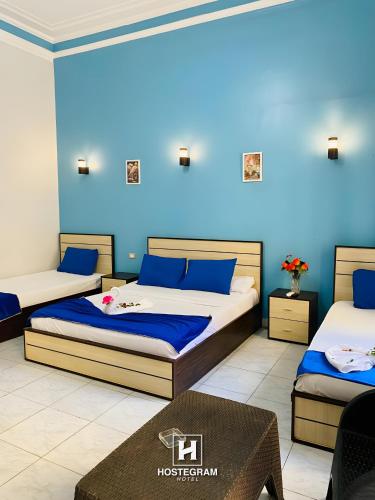 a room with two beds and a blue wall at Hostgram Hotel in cairo in Cairo