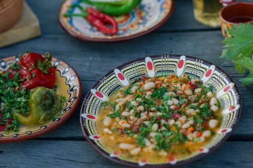 a table topped with plates of food with peppers at Authentic House with Stunning Mountain View - Karashka in Apriltsi