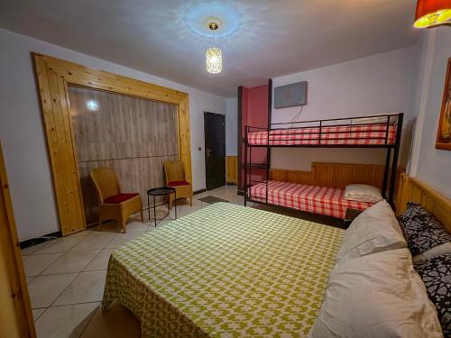 a bedroom with two bunk beds and a table and chairs at Senhaja Hôtel et Spa in Jenane Sidi Amer