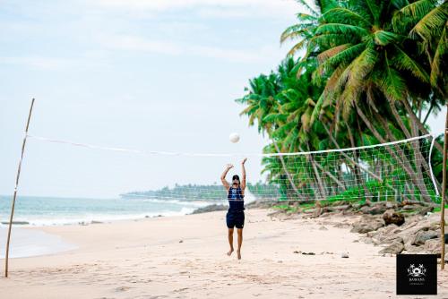 a woman jumping to catch a volleyball ball on the beach at BAWANS VILLA Holiday Home for Family or Group in Hikkaduwa