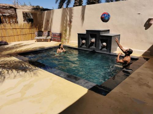 a group of people in a swimming pool with a fireplace at Siwa Oracle Hostel in Siwa