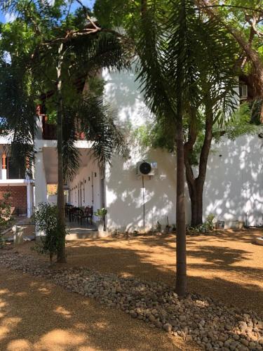 a white building with trees in front of it at Ovenro Hotel Yala, Kataragama in Kataragama