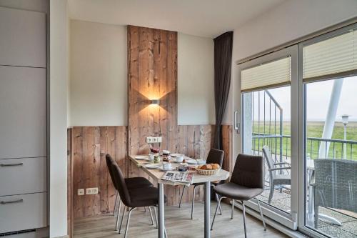 a dining room with a table and chairs and a balcony at Pamir - 25 in Cuxhaven