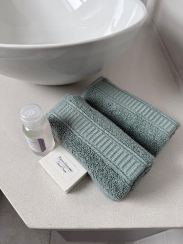 a bathroom counter with two towels and a bottle of medicine at Casa de Santos - Bougain Villa in Mossel Bay