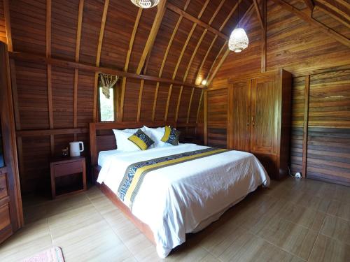 a bedroom with a large bed in a wooden room at Casa Matā Phitā Cottage in Patjung