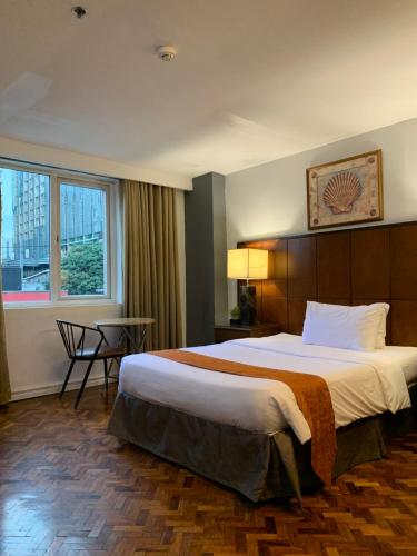a hotel room with a large bed and a window at Comfy Inn Manila-Kalaw in Manila