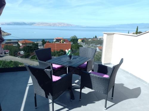 a table and chairs on a balcony with a view of the water at Natalija apartmani in Sveti Juraj