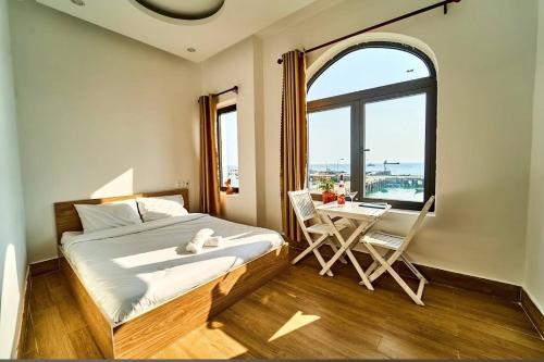 a bedroom with a bed and a table and a window at Chàm’s Corner Lookout Homestay & Restaurant in Tân Hiệp