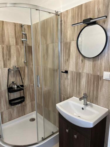 a bathroom with a shower and a sink and a mirror at Kawalerka z widokiem na jezioro in Ełk