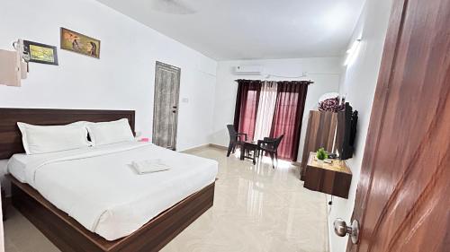 a bedroom with a bed and a table and a chair at Sunshine Guest House in Calangute