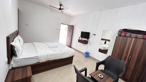 a small bedroom with a bed and a chair at Sunshine Guest House in Calangute