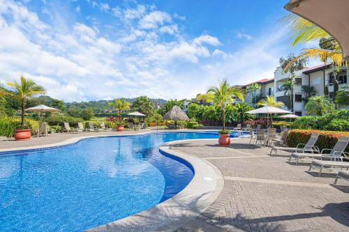 a swimming pool at a resort with chairs and umbrellas at Del Mar 5F 3 bdr Garden View in Los Suenos in Herradura