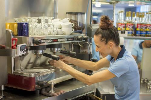 a woman in a kitchen using a coffee machine at Del Mar 5F 3 bdr Garden View in Los Suenos in Herradura