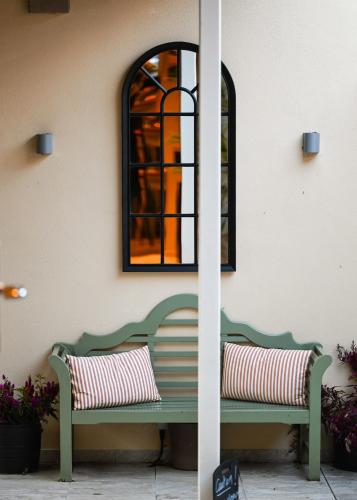 a green bench sitting next to a wall with a window at The Bakery B&B in Westerham